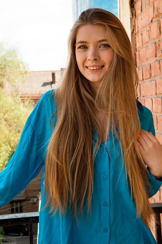 Девушка с длинными волосами позирует в голубой блузке